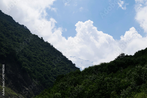 View of the mountains of the North Caucasus. Karmadon gorge. Mount Kazbek in the clouds. Mountains in the clouds in summer
