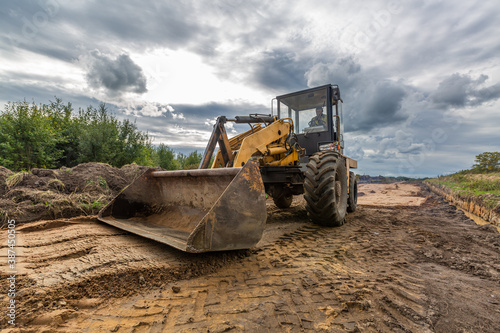 Road Construction and one of the construction machinery - bulldozer is flattenings the sand on the road before asphalting.
