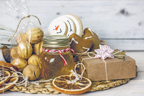 Homemade Christmas Food Gifts.Homemade cookies nuts, gingerbread, a jar of honey, dried oranges, a mixture for baking cookies in a jar on a wooden background. The concept of cozy, soulful DIY gifts