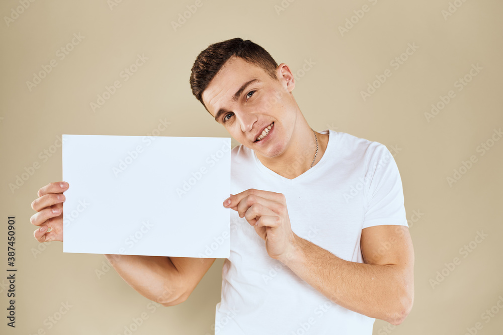 man in white t-shirt sheet of paper in hands Copy Space cropped view beige background