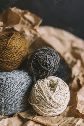 Cozy balls of yarn for hand knitting with dry oak leaf on a dark background. Autumn background for handmade and slow homelife.