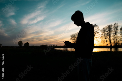 Silhouettes of a young man at sunset in the forest. Horizontal photo