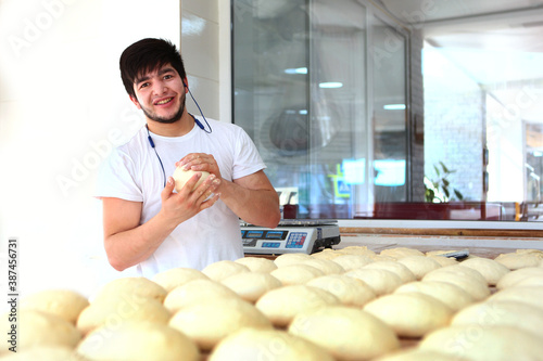 The baker prepares the tortillas dough. Yeast dough in the hands of a baker. The process of making tortillas. Horizontal photo. Light background.
