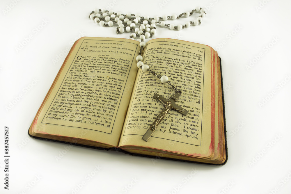 Obraz premium Opened catholic holy prayer book Treasury of the Sacred Heart and white beads crucifix with holy cross isolated on a white background