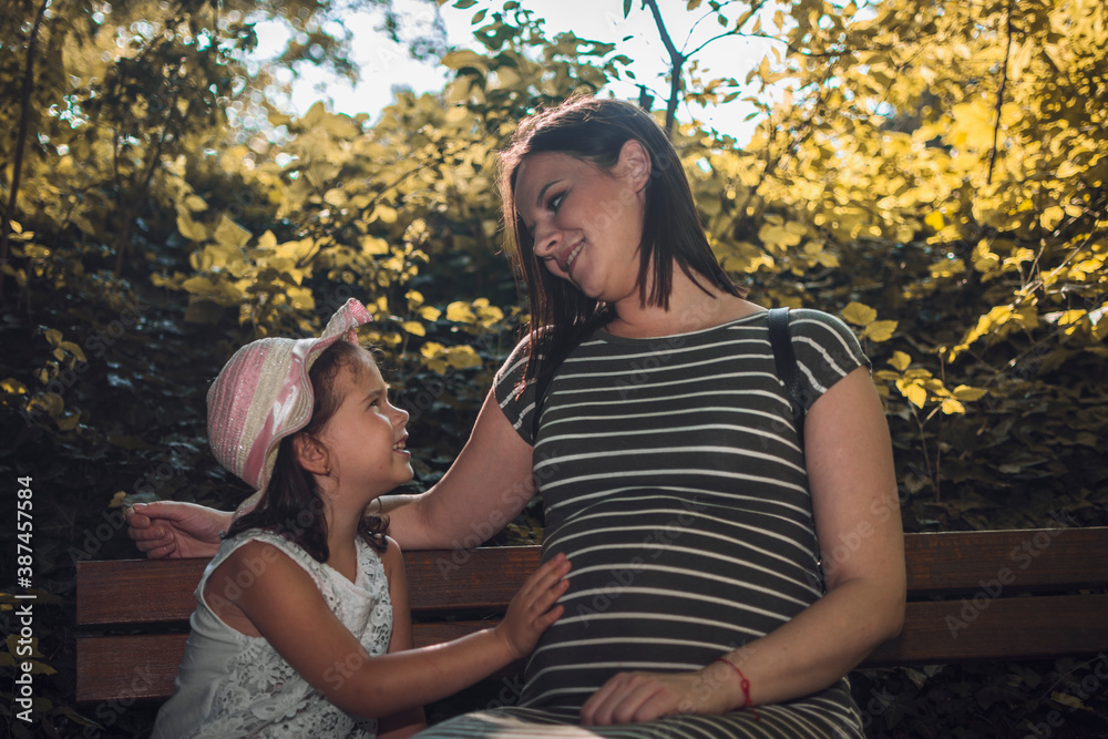 Pregnant mother with his daughter in a walk through the forest.