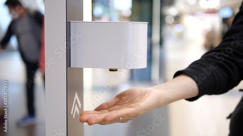 Close up of hand sprayed by contactless auto sanitizer dispenser device. Personal protection during coronavirus pandemic