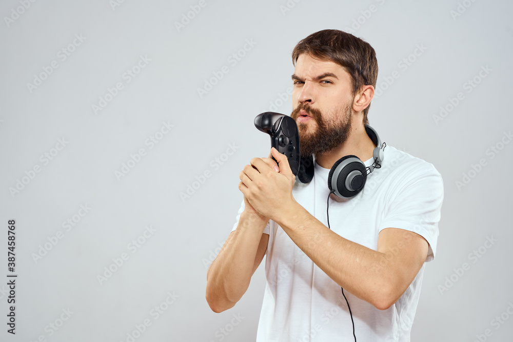 Man with gamepad headphones playing leisure technology white t-shirt light background Man with gamepad headphones playing leisure technology white t-shirt light background
