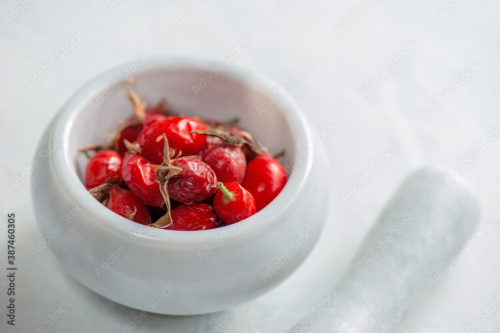 ripe rose hips in a stone mortar and pestle. Rosehip will be crushed to make vitamin tea. ripe rose hips in a stone mortar and pestle. Rosehip will be crushed to make vitamin tea.