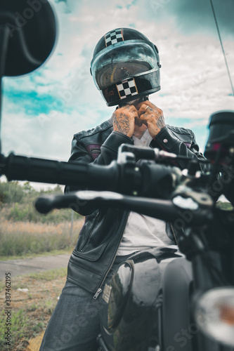 Motociclista hombre mexicano en carretera sobre su motocicleta con chaqueta de cuero y botas