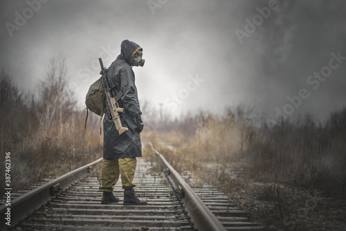 A post apocalypse soldier with a rifle is walking on the railroad. photo
