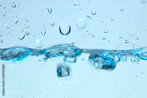 Nahaufnahme einer blauen Wasseroberfläche mit Wassertropfen und Luftblasen.