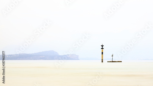 The view past a marker post across Lake Garda from the resort town of Sirmione. Sirmione is at the southern end of the lake which is in North East Italy.