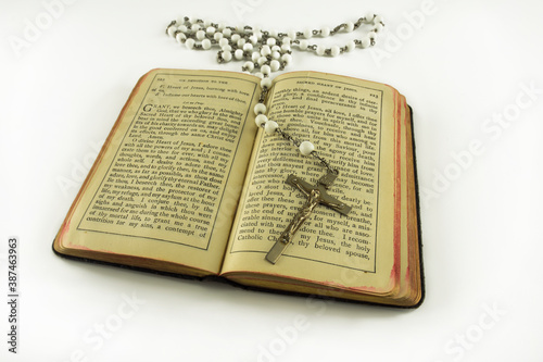 Opened catholic holy prayer book Treasury of the Sacred Heart and white beads crucifix with holy cross isolated on a white background photo