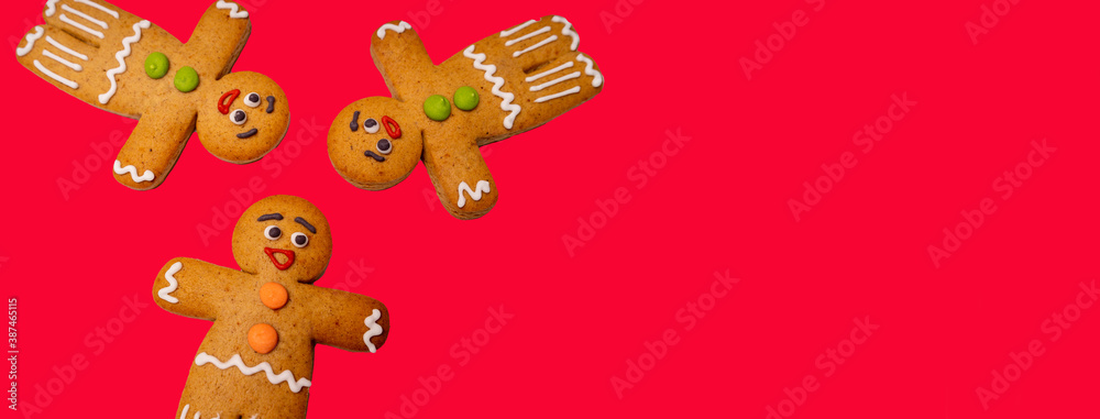 Close up of gingerbread men on red background. Festive decorative gingerbreads for Christmas mood with space for your text. Concept of classic cookie on holiday.