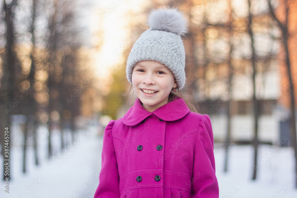 Happy young girl having fun in a winter park. Winter holidays concept. Girl outdoors. Gilr wearing pink coat and knitted hat walking on a beautiful day. Happy young girl having fun in a winter park. Winter holidays concept. Girl outdoors. Gilr wearing pink coat and knitted hat walking on a beautiful day.