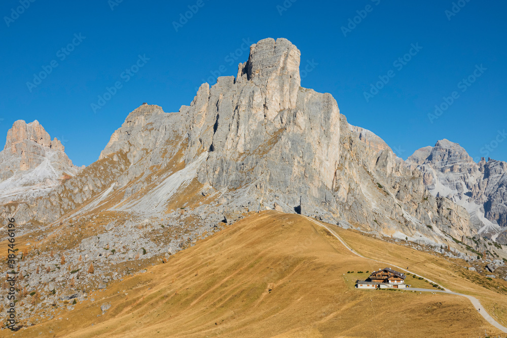 AERIAL: Beautiful rocky ridge towers over the golden meadows in Passo Giau.