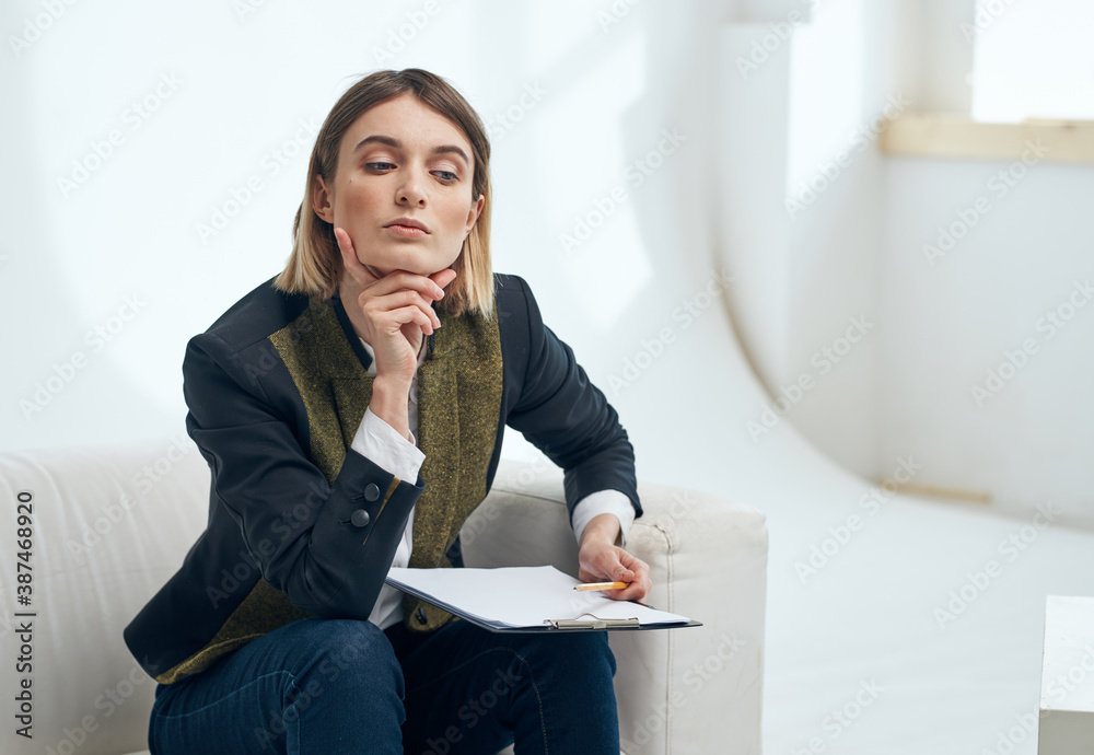 Business woman indoors with documents sits on the sofa near the window Business woman indoors with documents sits on the sofa near the window