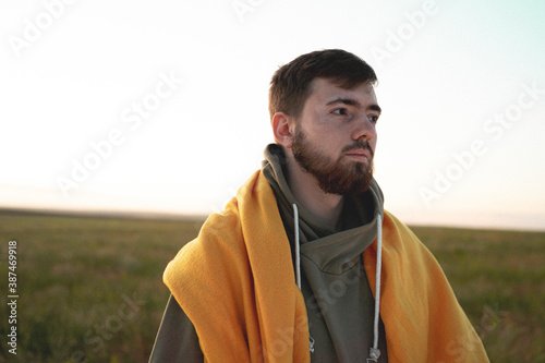 A bearded guy in a sweatshirt on the background of a green field.