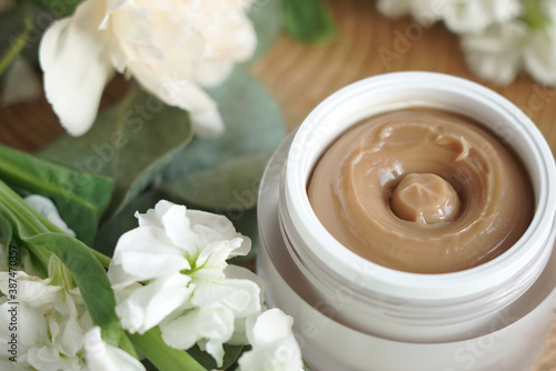 face cream, brown, against flowers