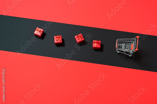 Gift boxes and shopping cart on black and red background. Black Friday sale concept