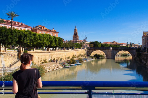 girl on bridge watching the safe river as it passes through murcia