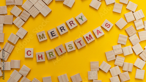 Happy New Year and Merry Christmas. Scrabble letters on yellow background. Letter tiles spelling celebration holiday.