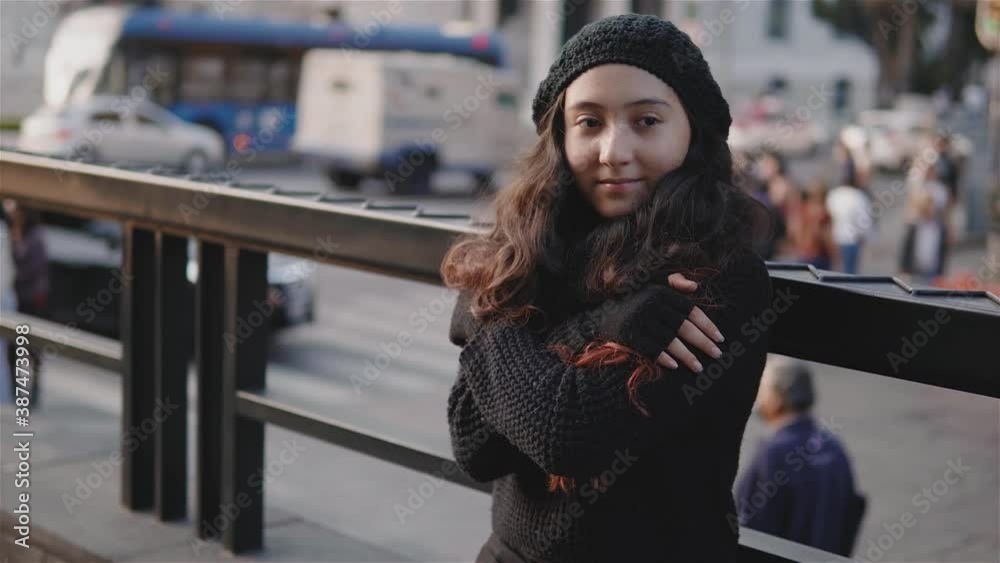 Vista de una adolescente por las calles de la Ciudad de México con ropa de abrigo en una tarde de otoño, una niña se frota porque tiene frio, imagen urbana con una niña con el sol al frente