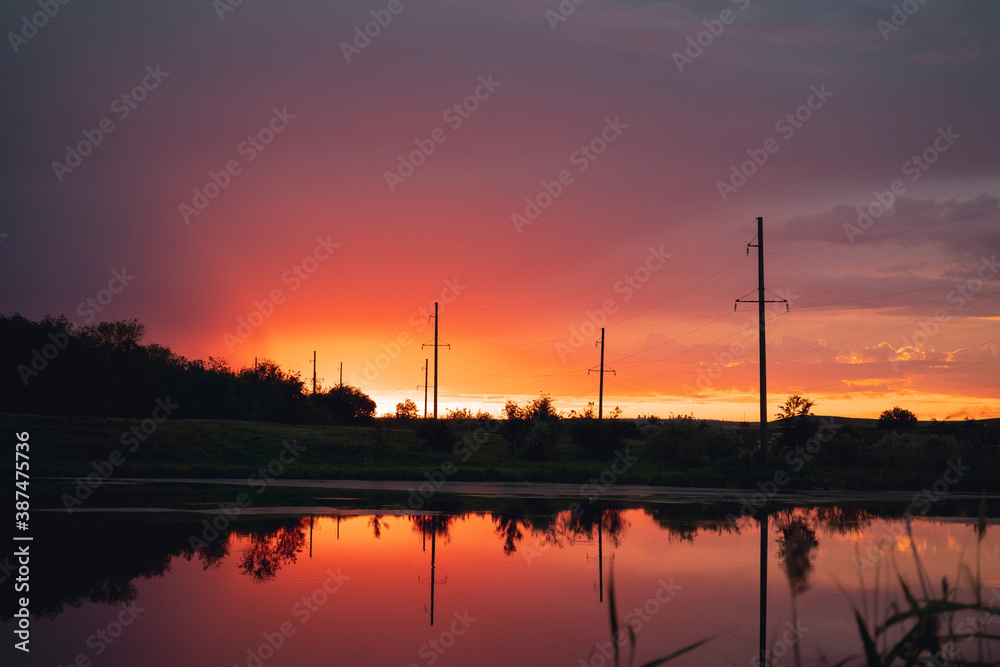 Naklejka premium Reflection of a scarlet fiery sunset in the river in the middle of the forest.