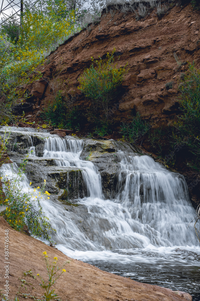 Obraz premium Steppe waterfall among the clay mountain walls. Green trees and grass