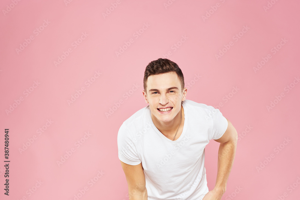 Cheerful handsome man in white t-shirt emotions pink isolated background Cheerful handsome man in white t-shirt emotions pink isolated background