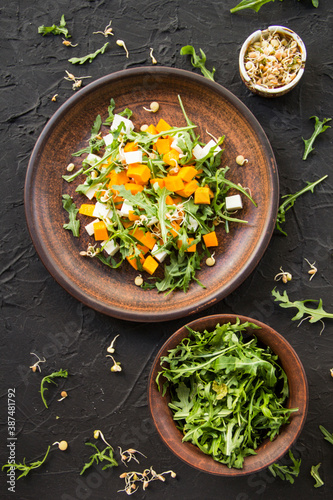 Delicious healthy pumpkin salad with arugula and cheese. Creative atmospheric decoration