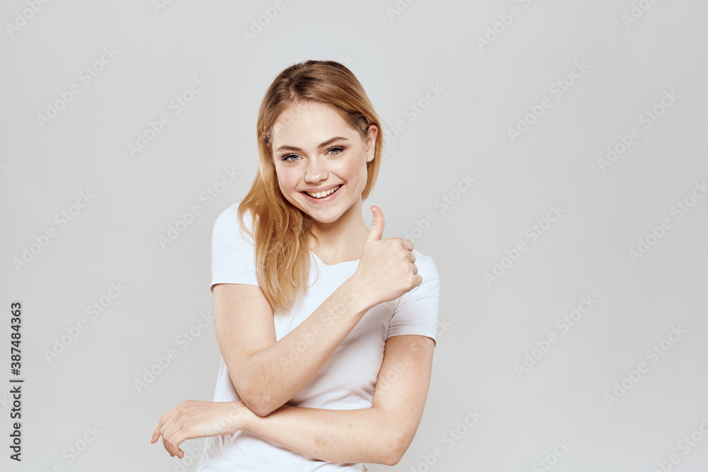 cheerful blonde in a white t-shirt gesturing with her hands light background cheerful blonde in a white t-shirt gesturing with her hands light background