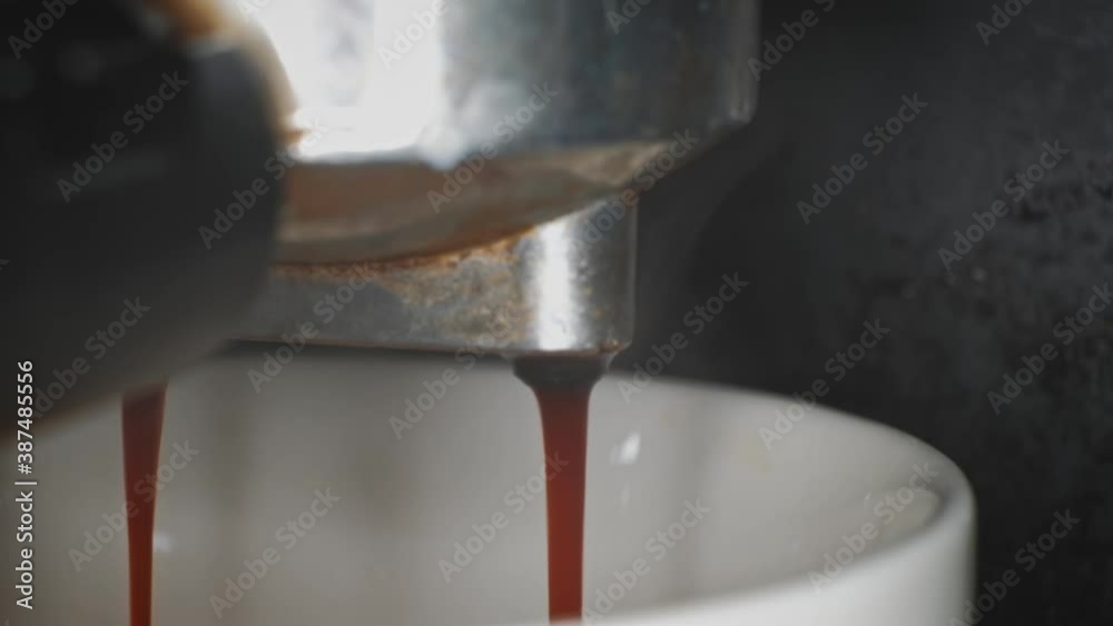 Coffee maker macro with dripping pouring coffe into cup from portafilter Coffee maker macro with dripping pouring coffe into cup from portafilter