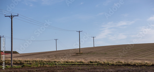 Two rows of powerlines crossing a stubble covered field