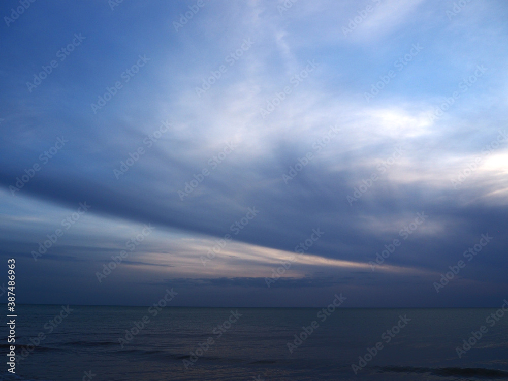 Dreamy ocean dusk with blowing clouds and rising tide