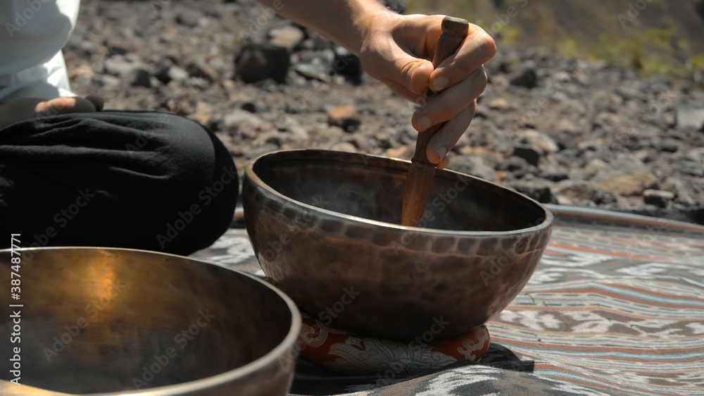 Asian guy playing Tibedt singing copper cups on a viewing mountain Asian guy playing Tibedt singing copper cups on a viewing mountain