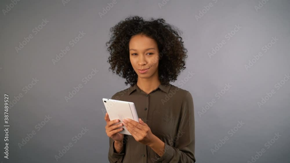 smiling young cute mixed race woman with tablet. on an isolated gray background, 4K smiling young cute mixed race woman with tablet. on an isolated gray background, 4K