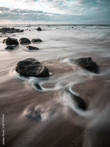 water flowing smoothly around stones at a beach at the North Sea, Germany (long exposure) photo