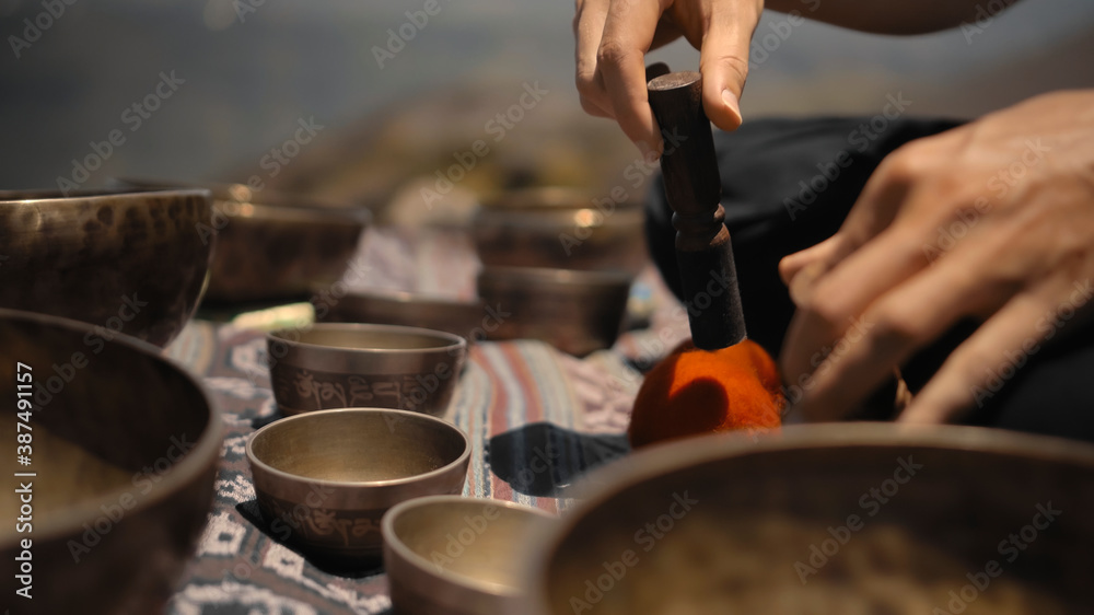 Asian guy playing Tibedt singing copper cups on a viewing mountain
