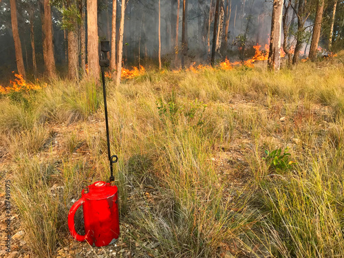 A drip torch with fire in the background