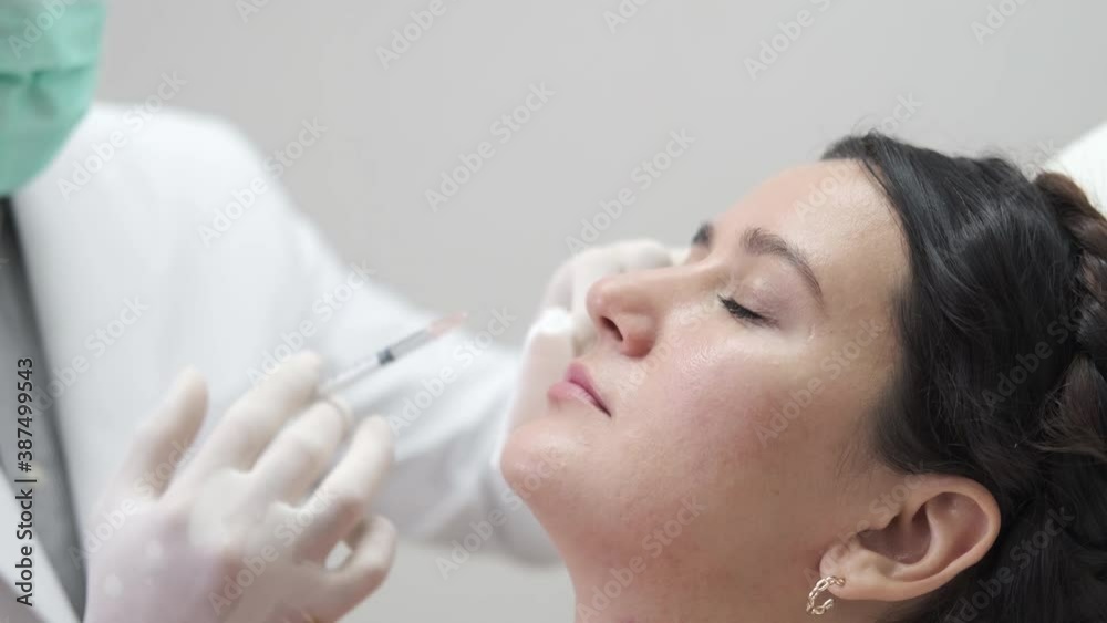 Young woman getting beauty facial injections in salon. Beautician makes cosmetic injection into the female patient face. Beauty injections, mesotherapy, revitalization and rejuvenation