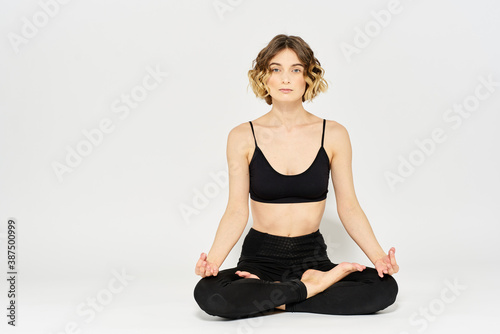 Woman in leggings meditate in a light room with her legs crossed yoga asana