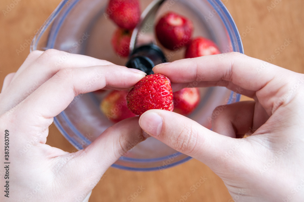 Hands put a strawberry in a blender, top view Hands put a strawberry in a blender, top view