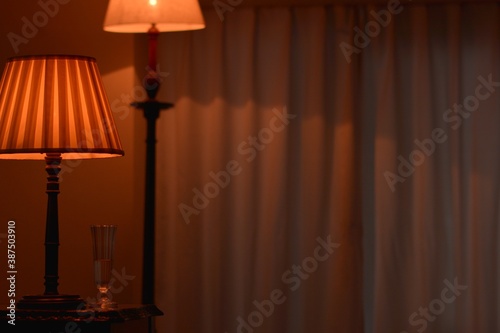 Room of the table shade lamp with stand lamp & champagne glass. dim lighting room soft focus image. This expensive antique mahogany furniture is made in England.