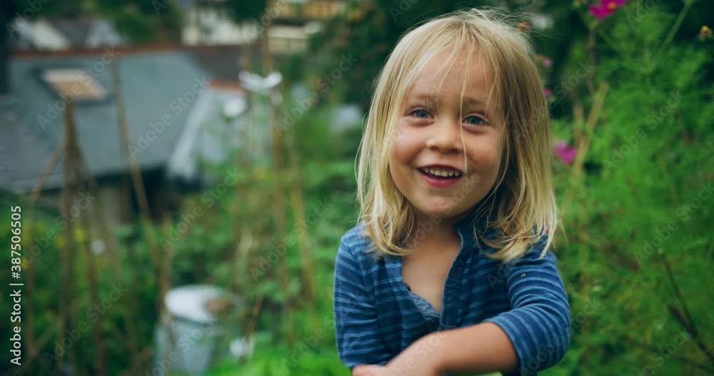 A little preschooler is hiding behind some lettuce leaves in a garden A little preschooler is hiding behind some lettuce leaves in a garden