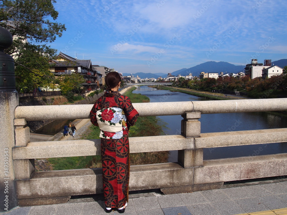 An Asian woman wearing a traditional Japanese kimono looking at the Kamo River, Kyoto, Japan