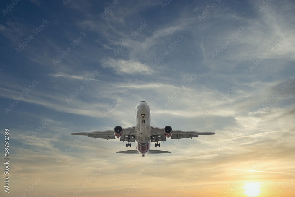 Airplane approaching with beautiful sunset in dramatic sky