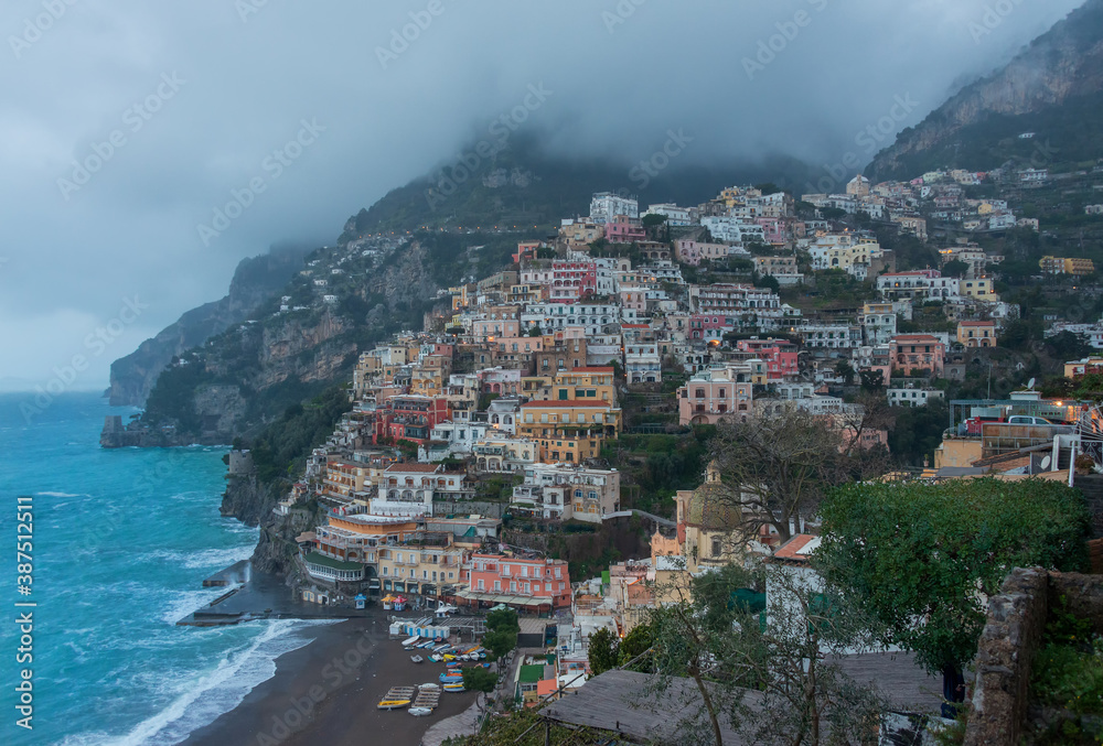 A high angle view of Positano with colorful buildings along the hillside. The morning atmosphere has fog over the city.