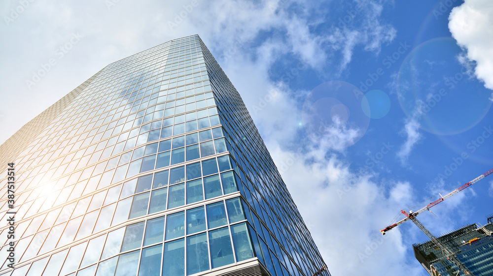 Bottom view of modern office buildings in the business district. Skyscraper glass facades on a bright sunny day with sunbeams in the blue sky. Bottom view of modern office buildings in the business district. Skyscraper glass facades on a bright sunny day with sunbeams in the blue sky.