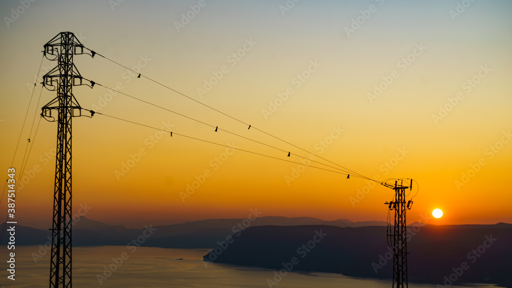 High voltage towers on coast at sunset